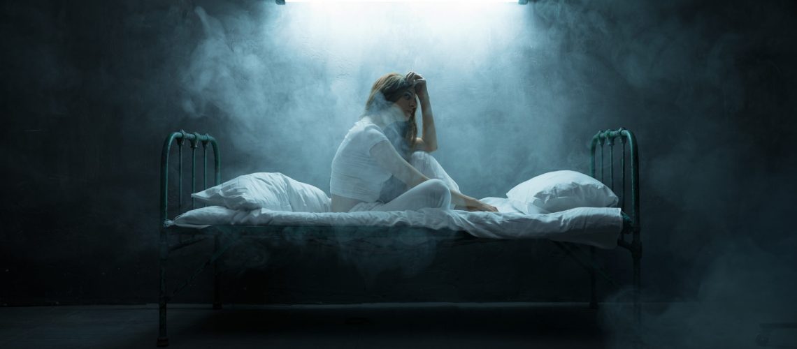 Depressed psycho woman sitting in bed, insomnia, dark room on background. Psychedelic female person having problems every night, depression and stress, sadness, psychiatry hospital