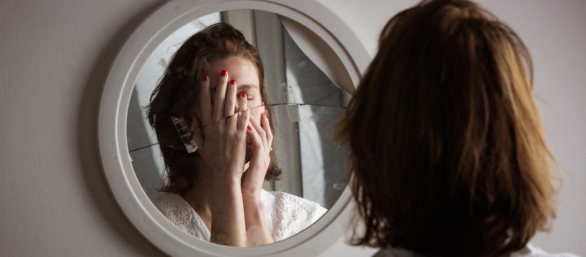 Reflection of a woman's face in broken mirror. Depression, anxiety, phobia, suicide and mental health concept.