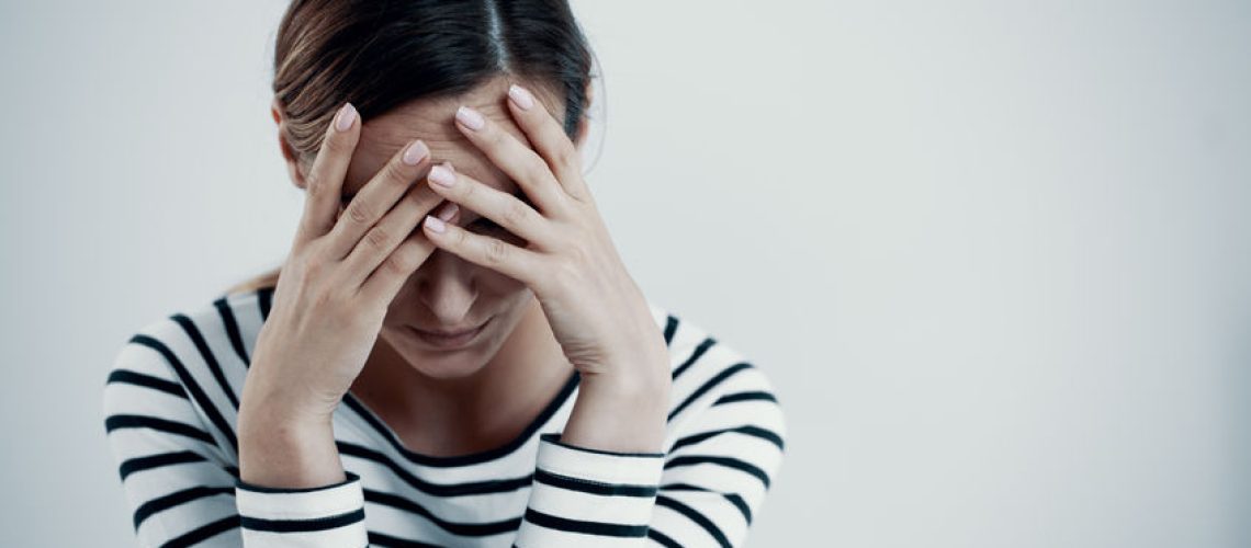 Overwhelmed young mother suffering from impulse control and addiction disorder, copy space on the empty white wall